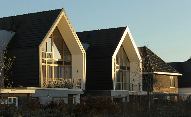 Moderne woning met kenmerkende zadeldaken, grote panoramische ramen en stijlvolle architectonische details in een suburbane omgeving.