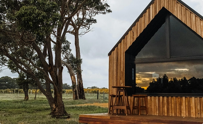 Stijlvolle houten cabin met grote panoramische beglazing, buitenterras en schilderachtige plattelandsomgeving, ideaal voor een rustige retraite.